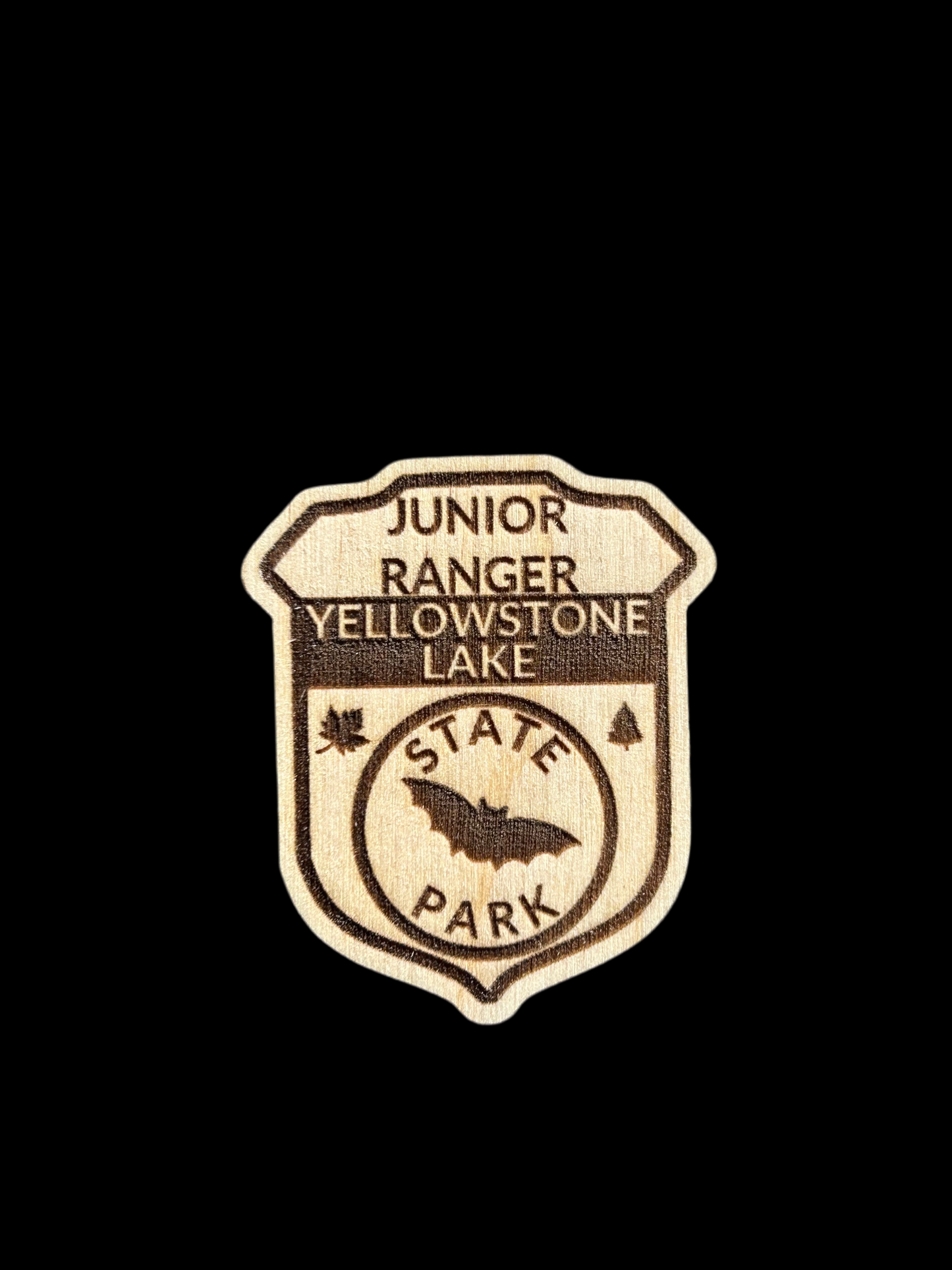 Wood badge shaped junior ranger pin with text Yellowstone Lake State Park and bat icon. 