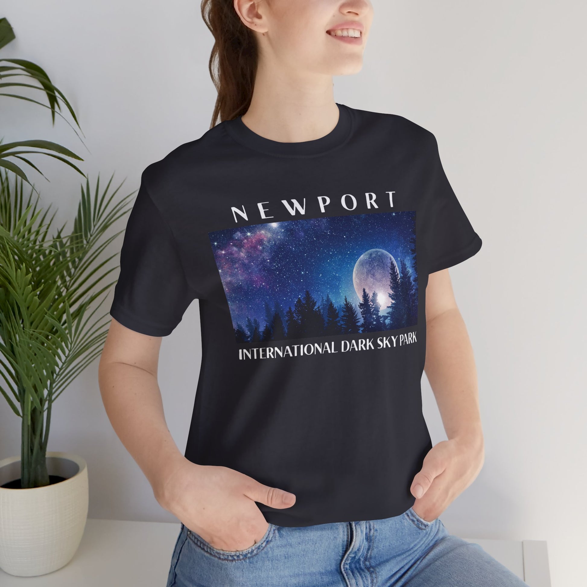 Person wearing a dark grey t-shirt with 'Newport International Dark Sky Park' design