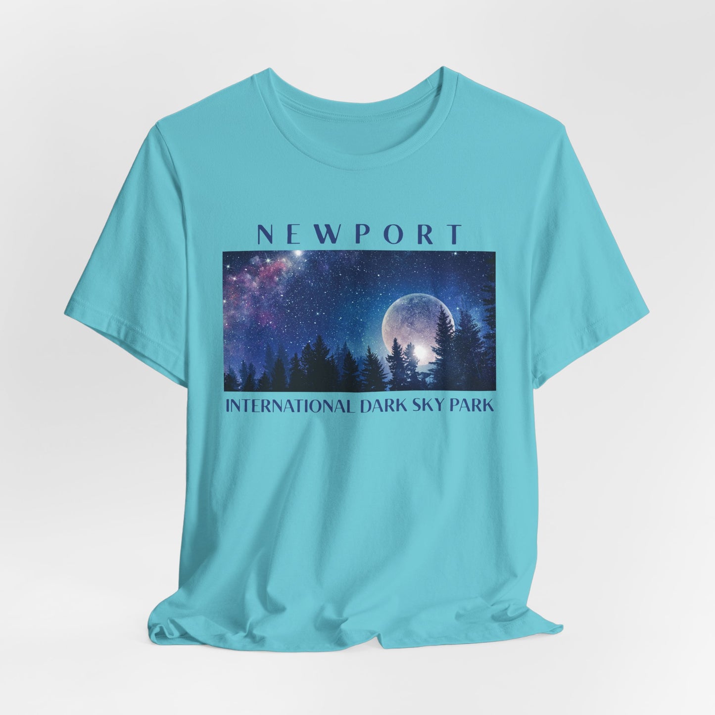 Tourquise t-shirt with a graphic of a night sky over trees and the text 'Newport International Dark Sky Park'.