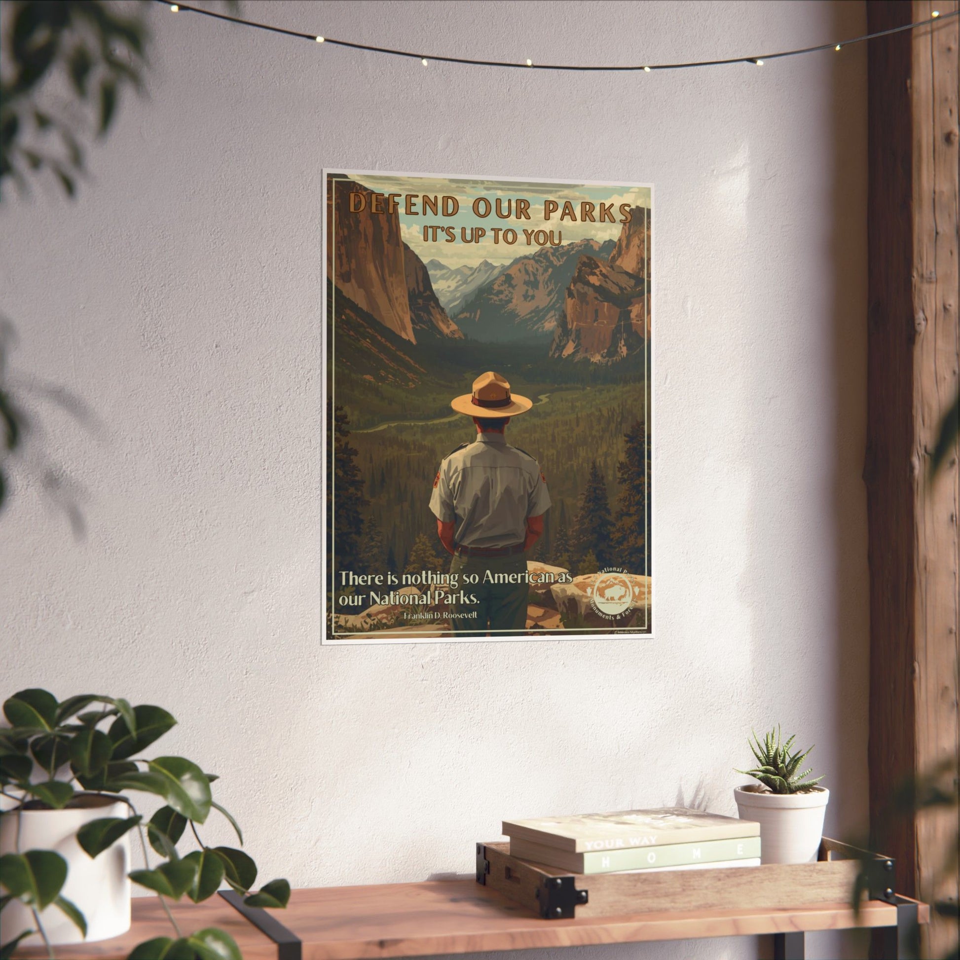 Poster depicting a Park Ranger overlooking a scenic mountain valley with the text “Defend our Parks-it’s up to you!” Photo background: poster in a wall above a wood shelf and potted plants.
