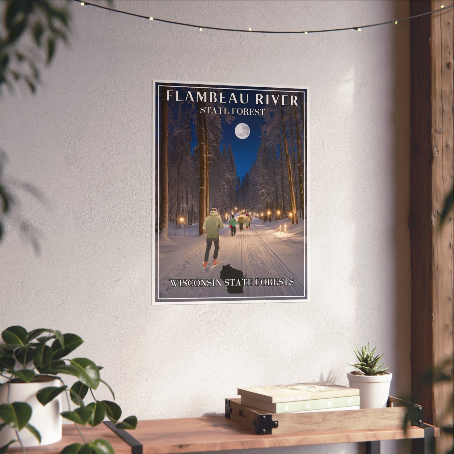 18x24” poster depicting a skier and snowshoers going down a candlelight trail through the woods and towering pines.  Photo background: poster hanging on a wall above a shelf with books and plants.