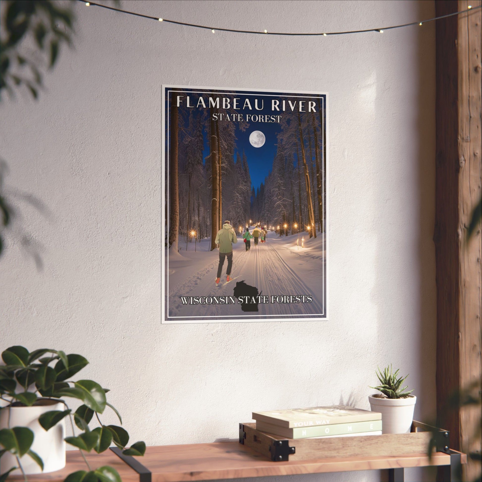 18x24” poster depicting a skier and snowshoers going down a candlelight trail through the woods and towering pines.  Photo background: poster hanging on a wall above a shelf with books and plants.