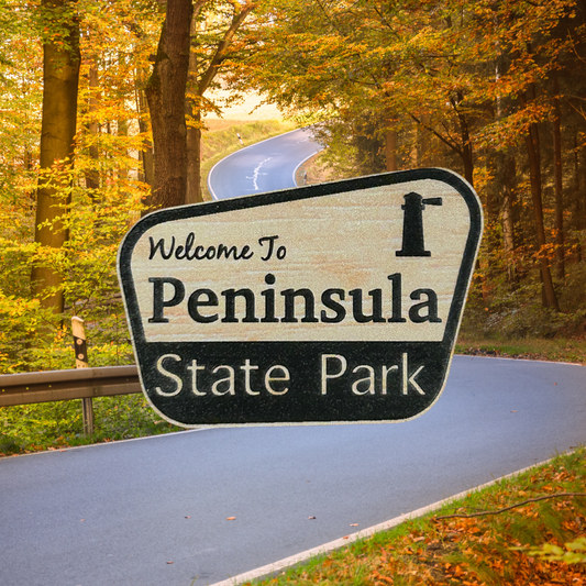 Wood grain acrylic magnet with “welcome to Peninsula State Park” and lighthouse icon.  Photo background: winding road through fall trees.