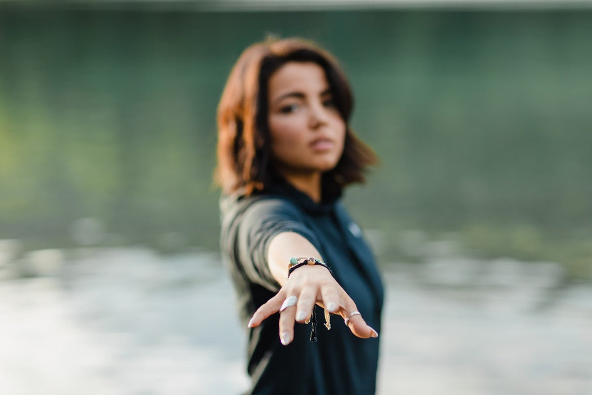 Woman extending her hand towards the camera with a blurred natural background
