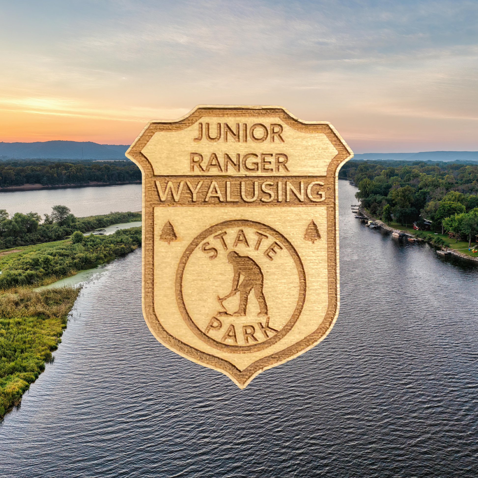 Wooden badge with 'Junior Ranger Wyalusing State Park' text with a miner icon.  Photo background a scenic view of a river and trees.