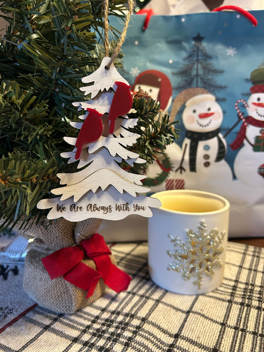 Two frosted cranberry colored cardinals on a wood tree ornament with the text “we are always with you.”