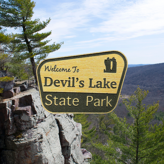 Engraved wood grain acrylic with “Welcome to Devil’s Lake State Park”.  Photo background: bluff overlooking a rock ledge and wooded valley. 