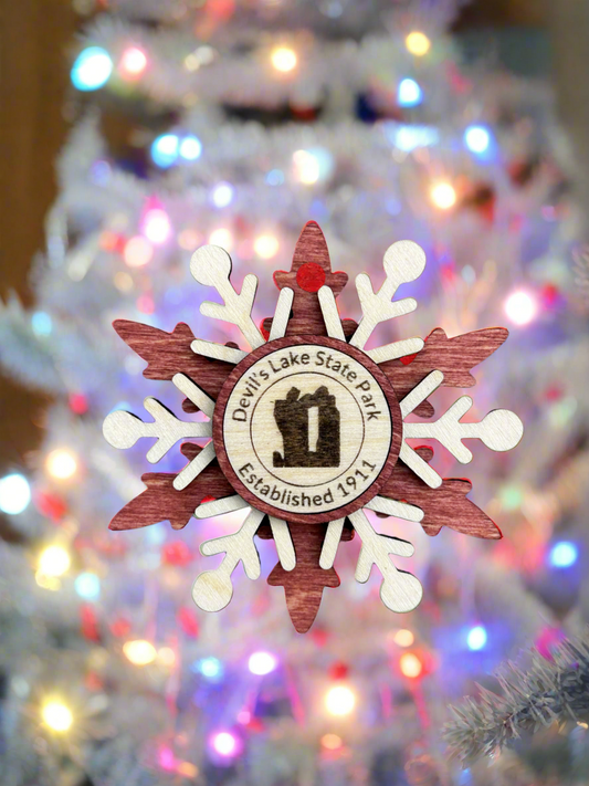 Red wood snowflake ornament with text Devil's Lake State Park and Devil's Rock symbol. 