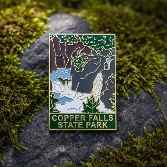 Pin with Copper Falls State Park design on a rock with green moss