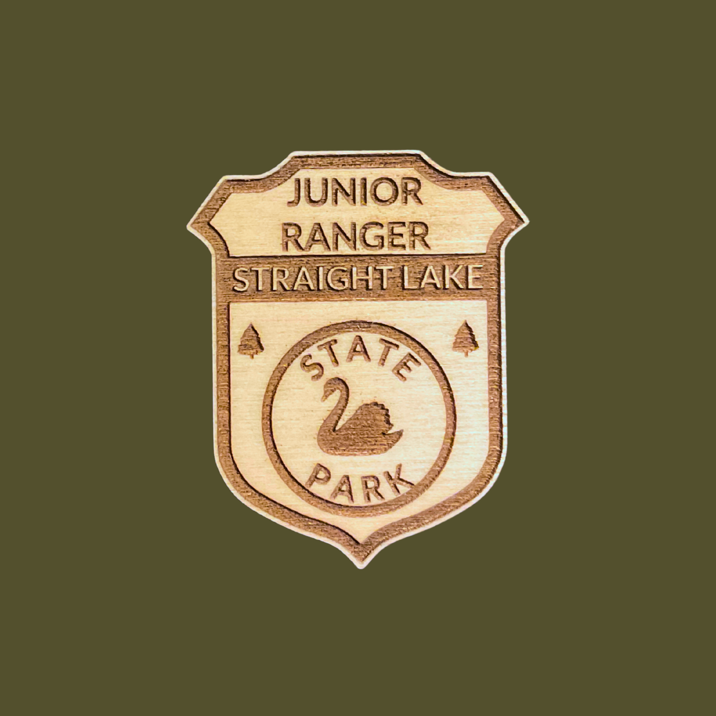 Wood Junior Ranger Badge featuring a swan icon with the text: Junior Ranger Straight Lake State Park.  Photo background: olive drab color.
