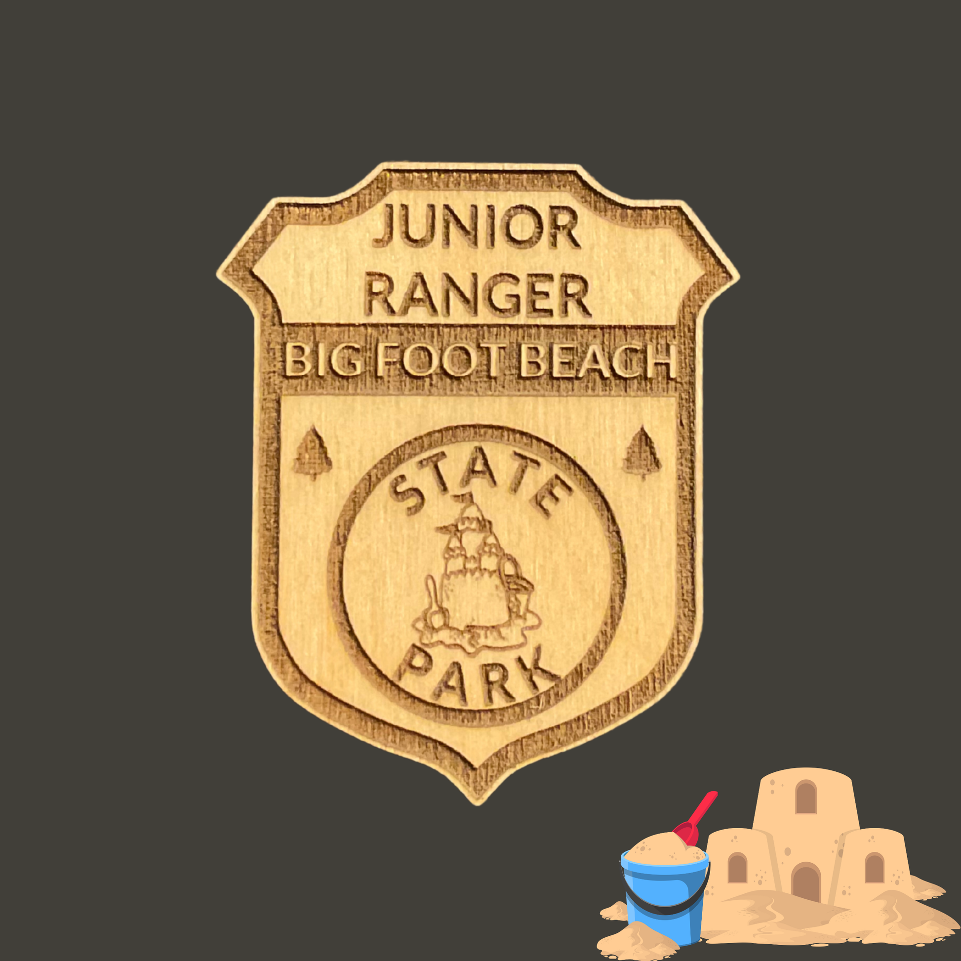 Laser engraved wood badge featuring the text: “Junior Big Foot Beach State Park” with the icon of a sandcastle.  Photo Background: dark grey background with clip art image of a sandcastle.