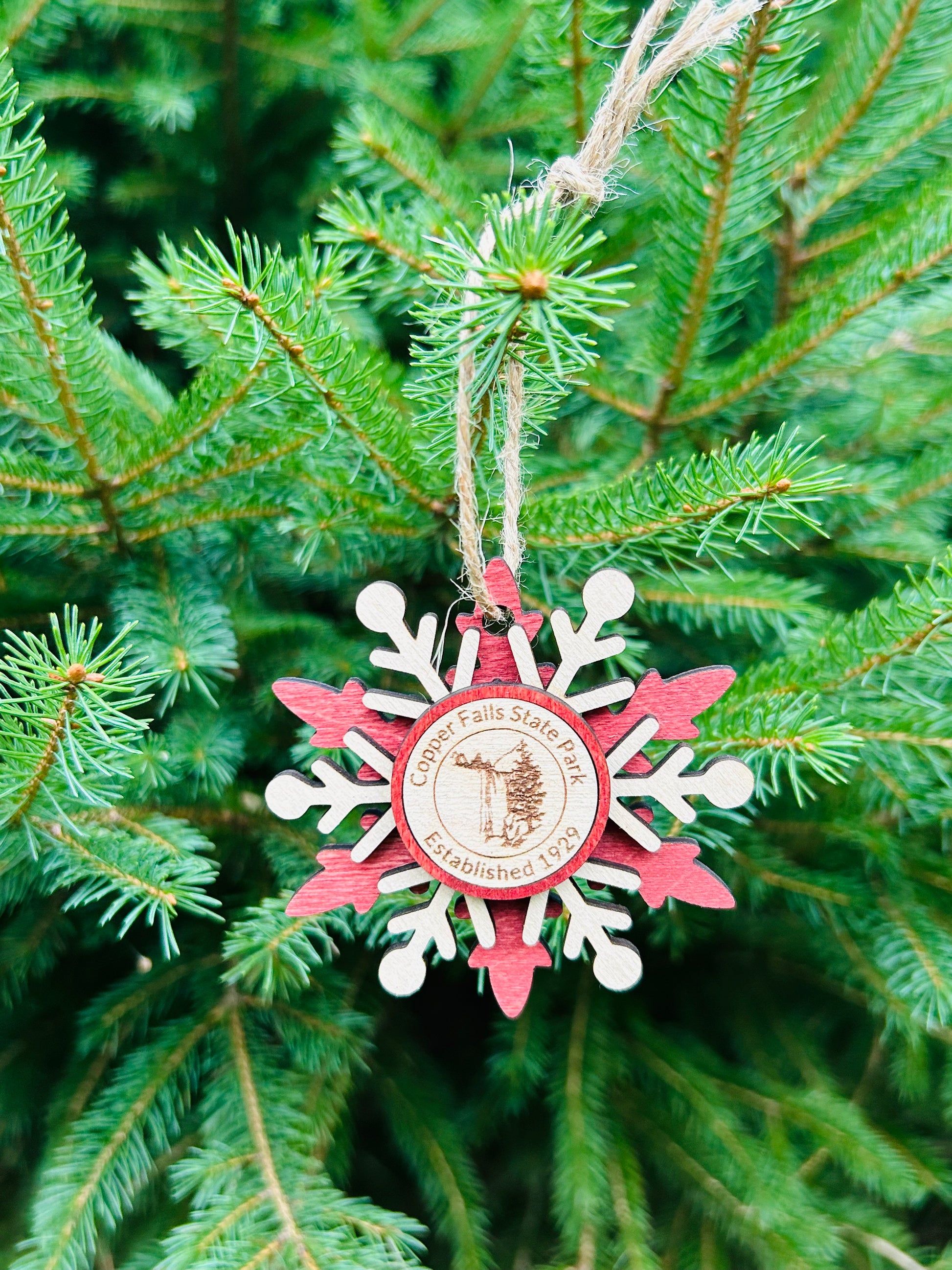 Red wood snowflake ornament with text Copper Falls and waterfall symbol. 