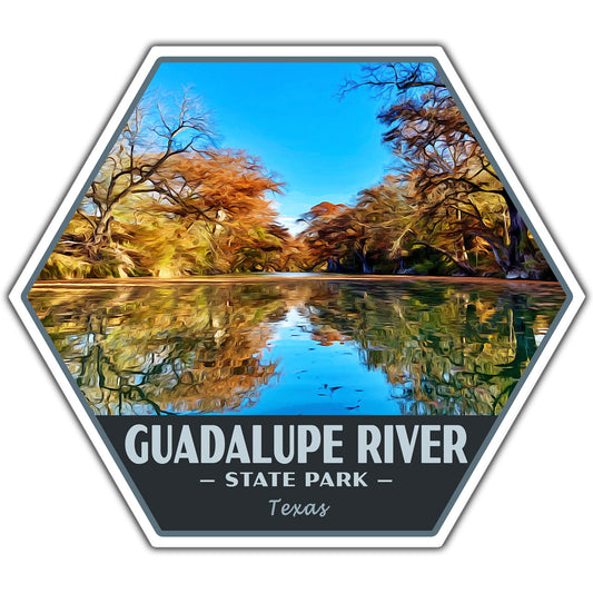 A hexagonal sticker featuring a stylized landscape of the Guadalupe River in Texas, with autumn trees reflected in blue water under a clear blue sky. The bottom section is dark gray with white text reading 'GUADALUPE RIVER - STATE PARK - Texas'.