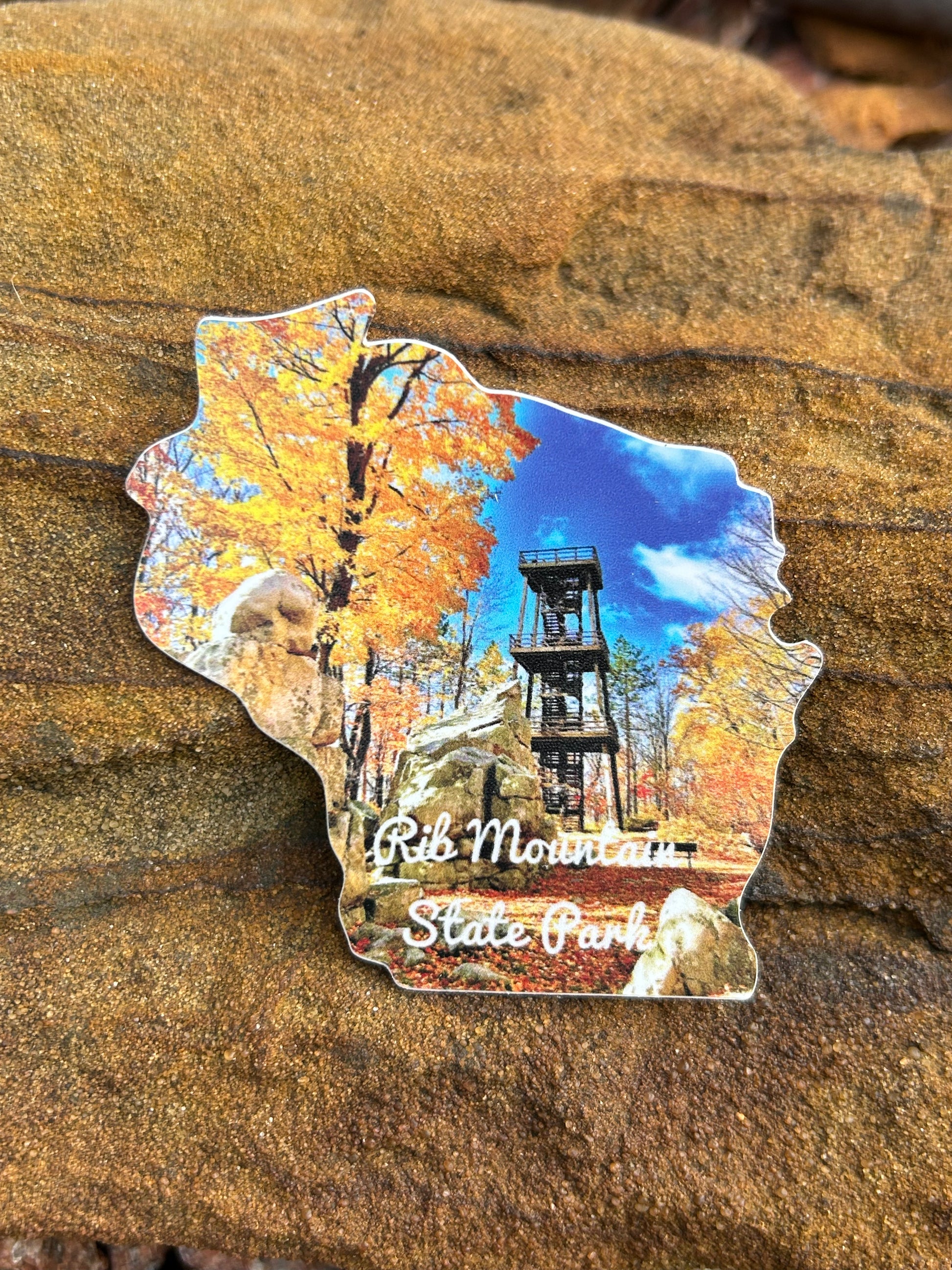 Wisconsin Shaped sticker with a photograph of fall color trees and observation tower, and the text "Rib Mountain State Park". 