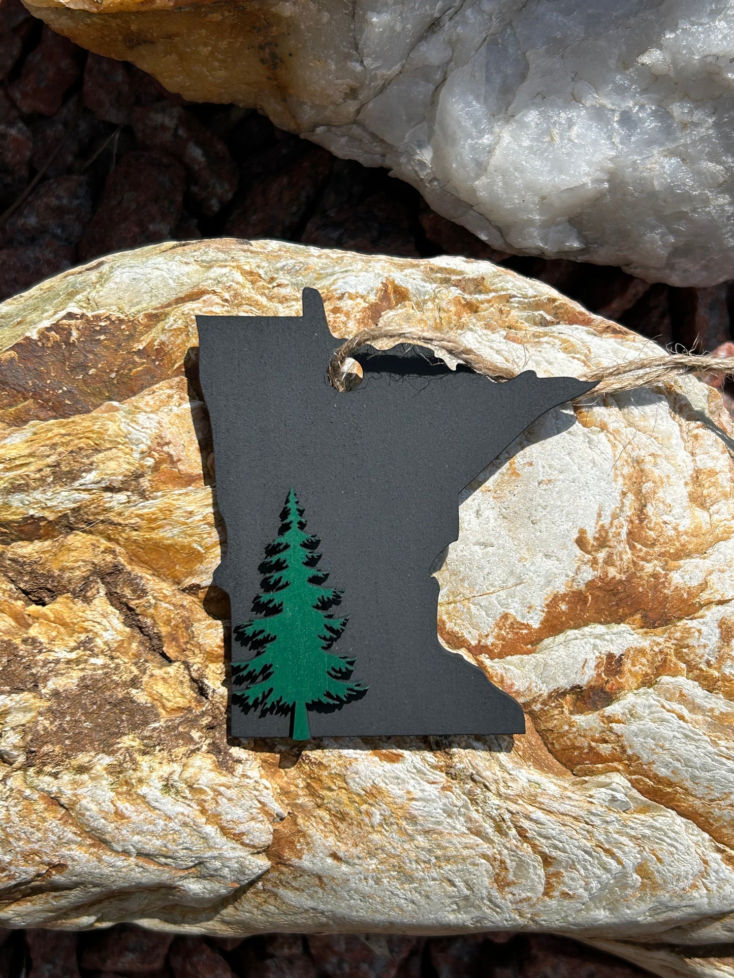 Black Minnesota Shaped ornament with a green pine tree icon. 