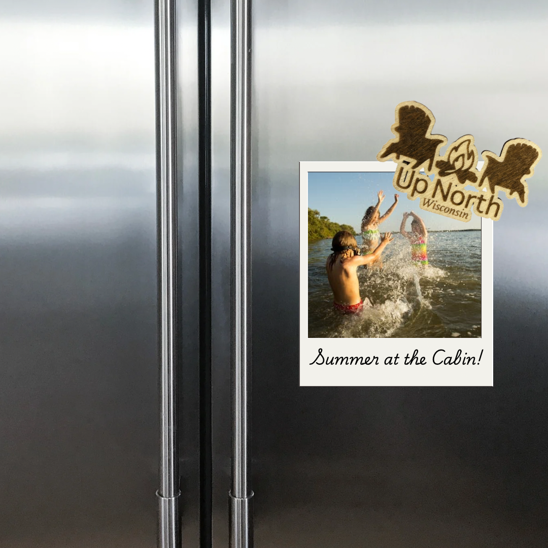 Wood magnet in the shape of two Adirondack chairs and a campfire pictured against a refrigerator backdrop.