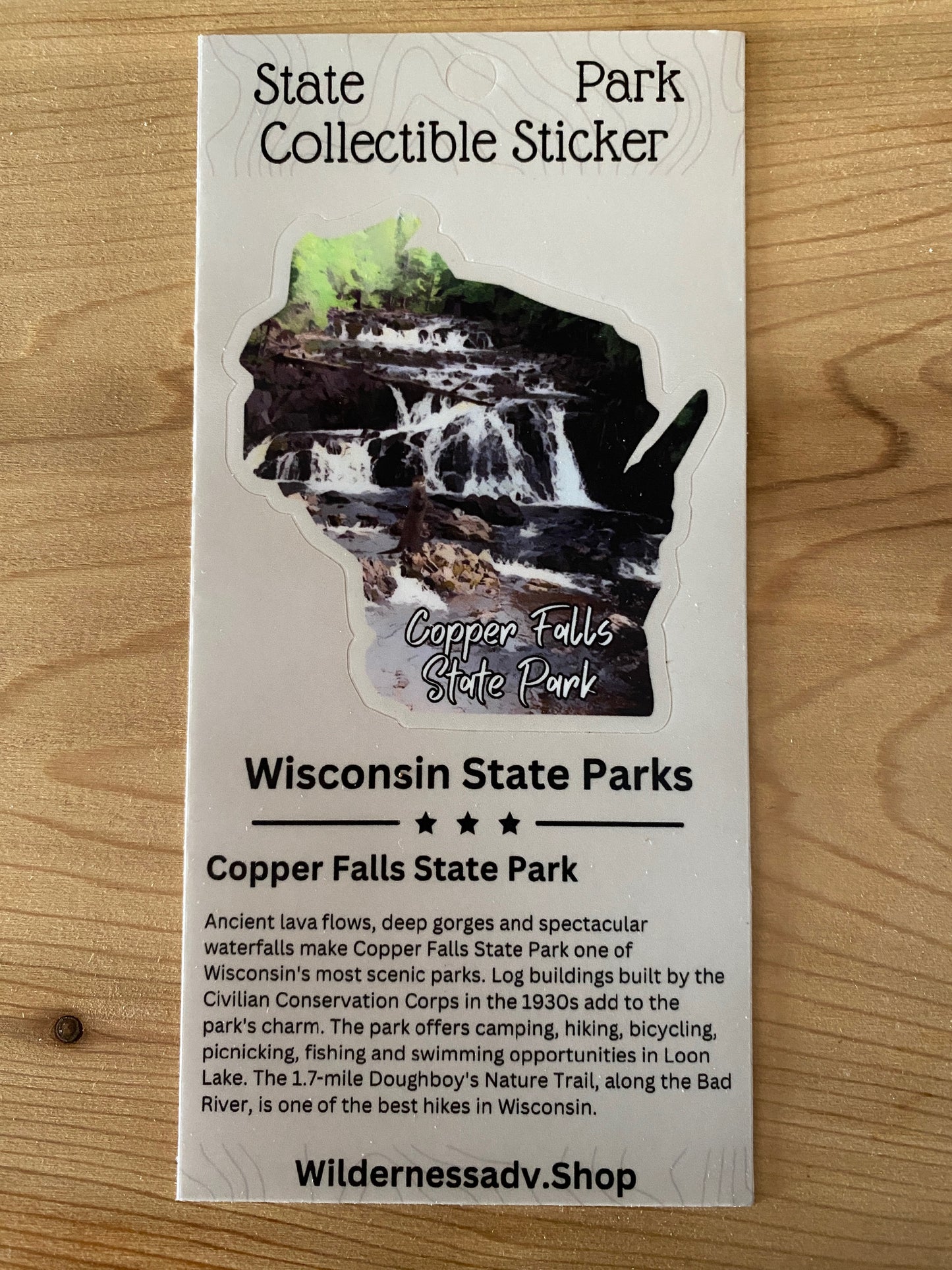 Wisconsin shaped sticker featuring the Tyler Forks Cascades and an otter.  Photo background: wood grain.