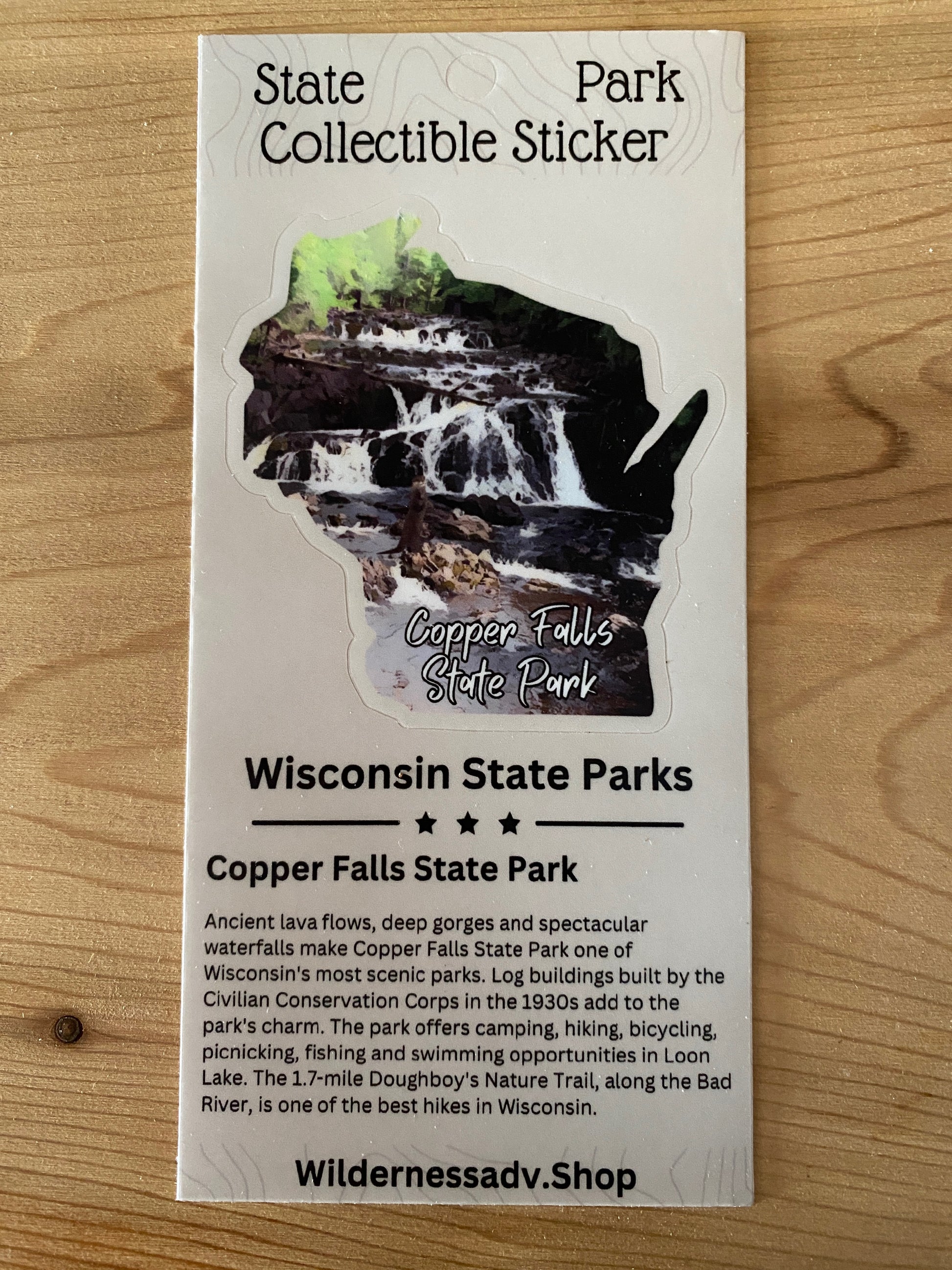 Wisconsin shaped sticker featuring the Tyler Forks Cascades and an otter.  Photo background: wood grain.
