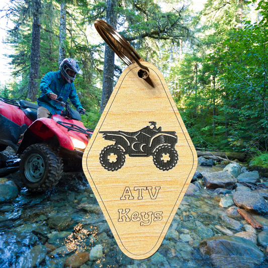 Wood grain acrylic keychains with ATV icon and text “ATV keys”.  Photo background: ATV crossing a wet and rocky stream.