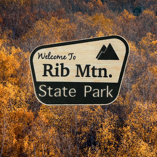 Wood grain acrylic magnet with “welcome to Rib Mtn. State Park” and mountain icon.  Photo background: Trees in fall leaf color.