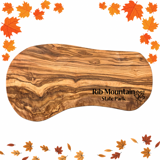 Natural olive wood serving board with the text “Rib Mountain State Park” and a maple leaf symbol engraved on it.  Photo background: fall leaf clipart.