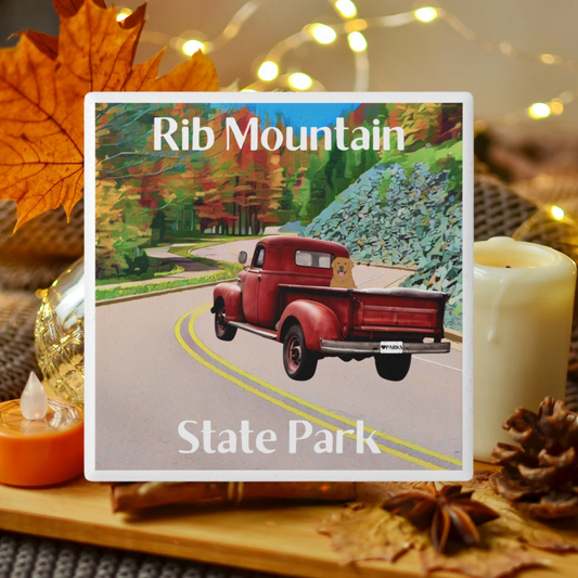 Ceramic Coaster featuring a vintage red truck driving down a road lined with trees in bright fall leaf color and the text: Rib Mountain State Park.  Photo background: pumpkins, leaves and candles. 