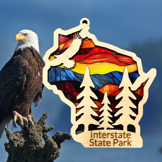 Wood Wisconsin shaped ornament with a stained glass appearance depicting an eagle soaring over trees and the text: Interstate State Park.  Photo Background: Eagle sitting on a branch.