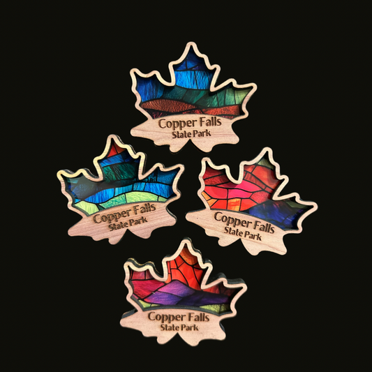 Four cedar maple leaf magnets with a faux stained glass appearance on a black background.