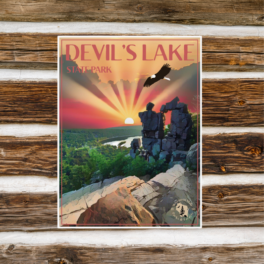 Poster featuring a majestic sunset over Devil’s Lake and Devil’s Doorway with an eagle flying above.  phot background: a rustic log wall with chinking. 