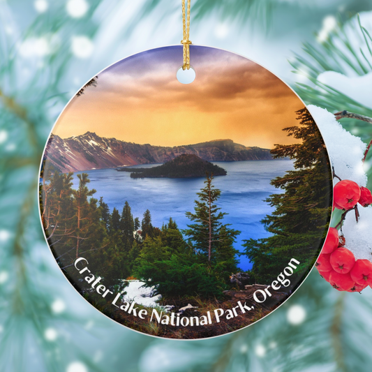 Round ceramic ornament featuring a vivid sunrise over Crater Lake design.  Photo background: snow covered tree.