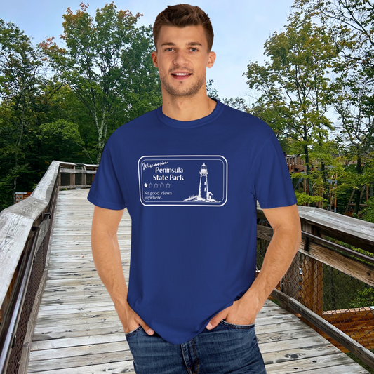 Male model wearing a Navy T-Shirt with 1 star review design of Peninsula State Park.  Features a line art image of a lighthouse, 1 star graphic, and the text: “Wisconsin Peninsula State Park, No good views anywhere.  Male is standing on Eagle Tower.