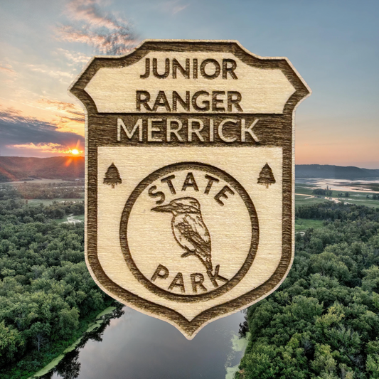 Wooden badge with 'Junior Ranger Merrick State Park' text over a scenic background