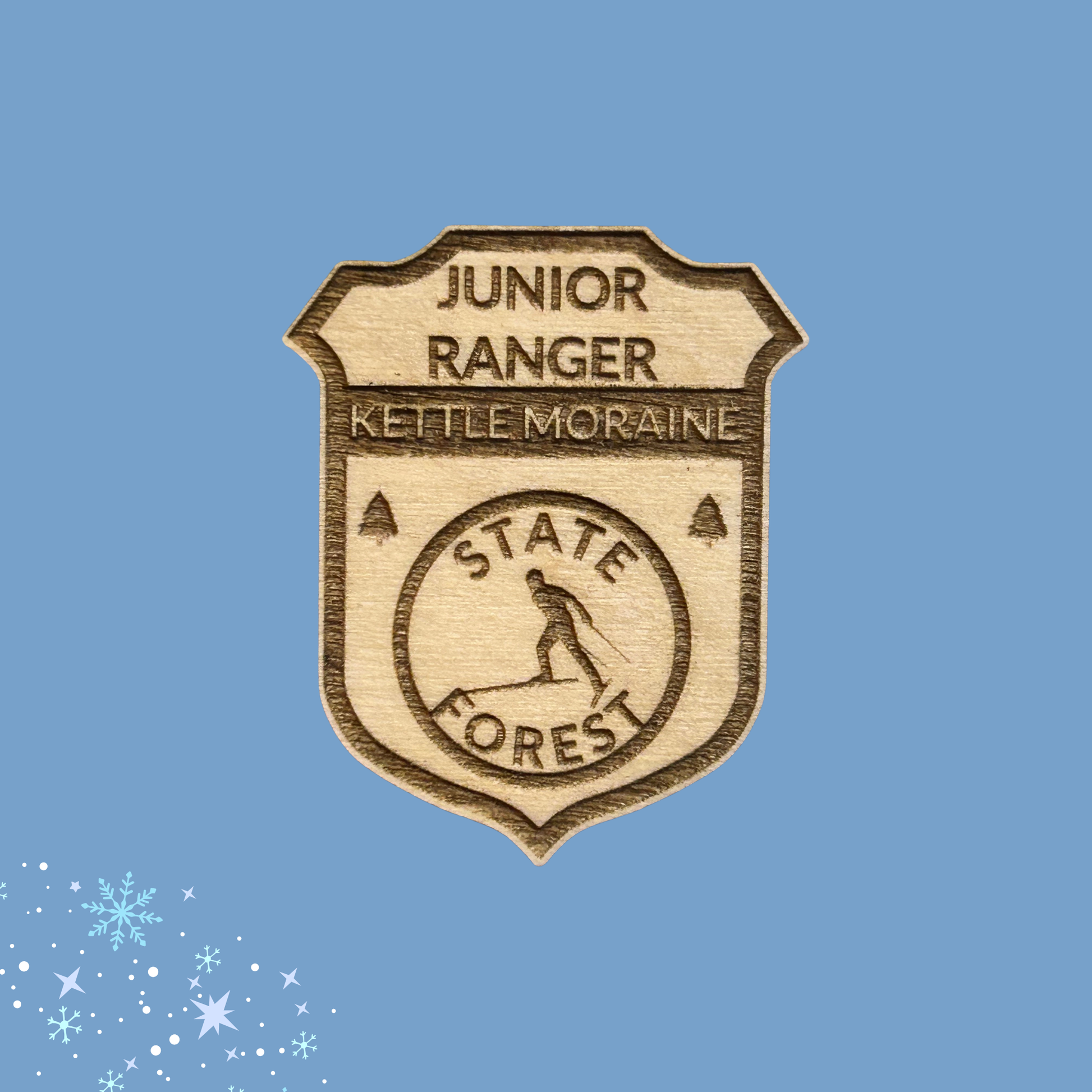 Junior Ranger badge for Kettle Moraine State Forest on a blue background with snowflake decorations.