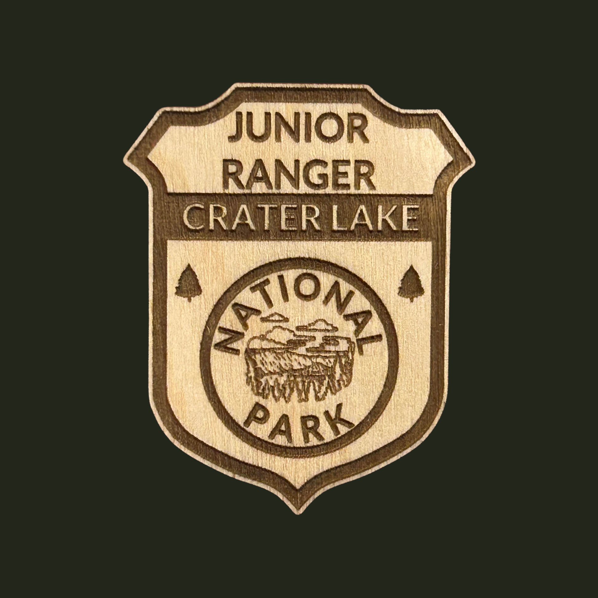 Wooden badge with 'Junior Ranger Crater Lake National Park' engraving on a black background