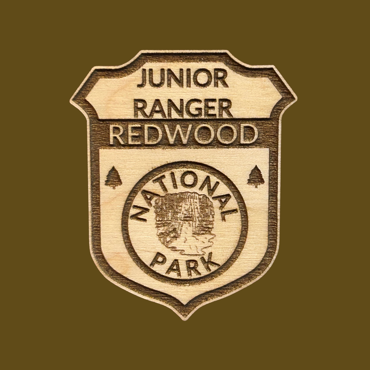 Wooden badge with 'Junior Ranger Redwood National Park' text on a brown background