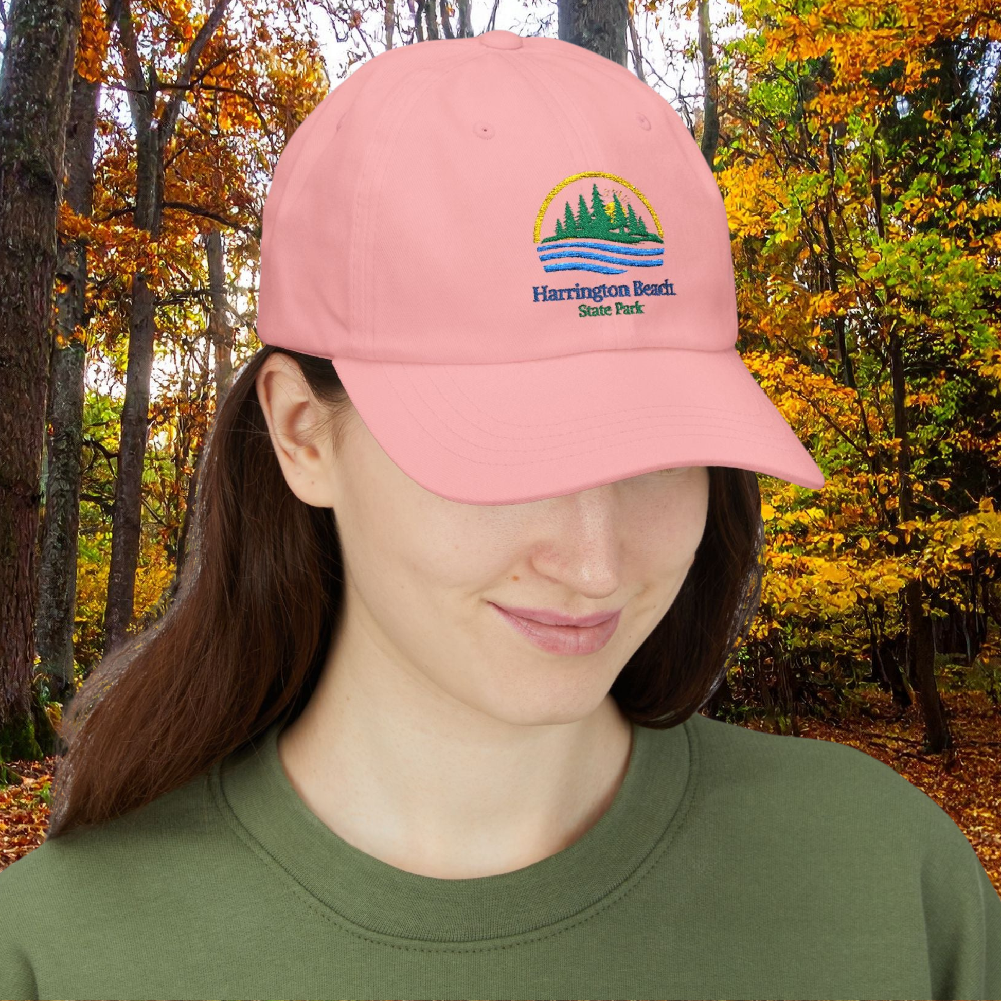 Person wearing a pink cap with Harrington Beach State Park logo against an autumn forest background