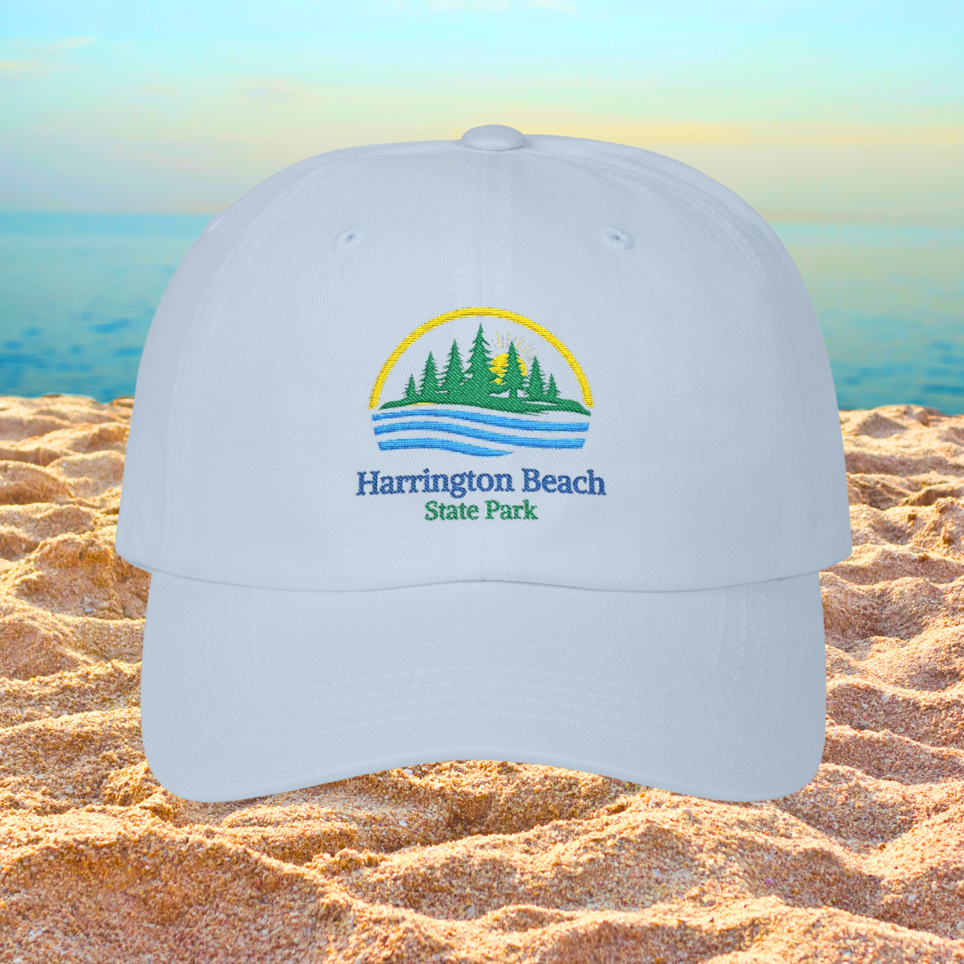 Light blue cap with Harrington Beach State Park logo on a sandy beach