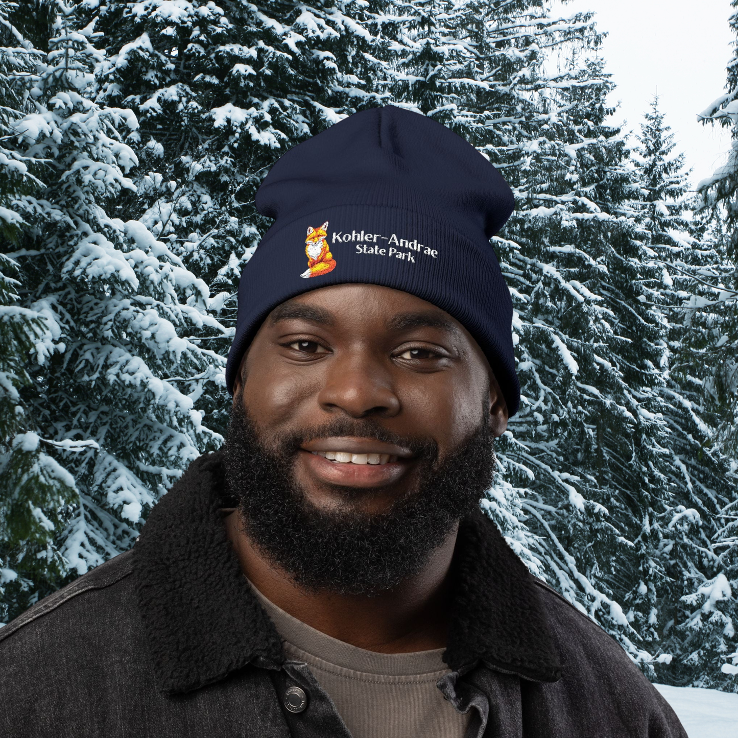 Person wearing a dark navy beanie with a Fox illustration and the text 'Kohler-Andrae State Park' in a snowy forest setting.