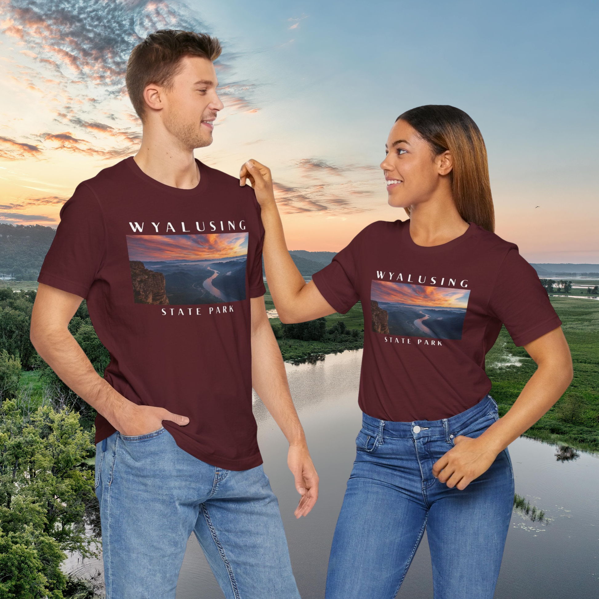 Two people wearing maroon t-shirts with Wyalusing State Park design against a scenic background.