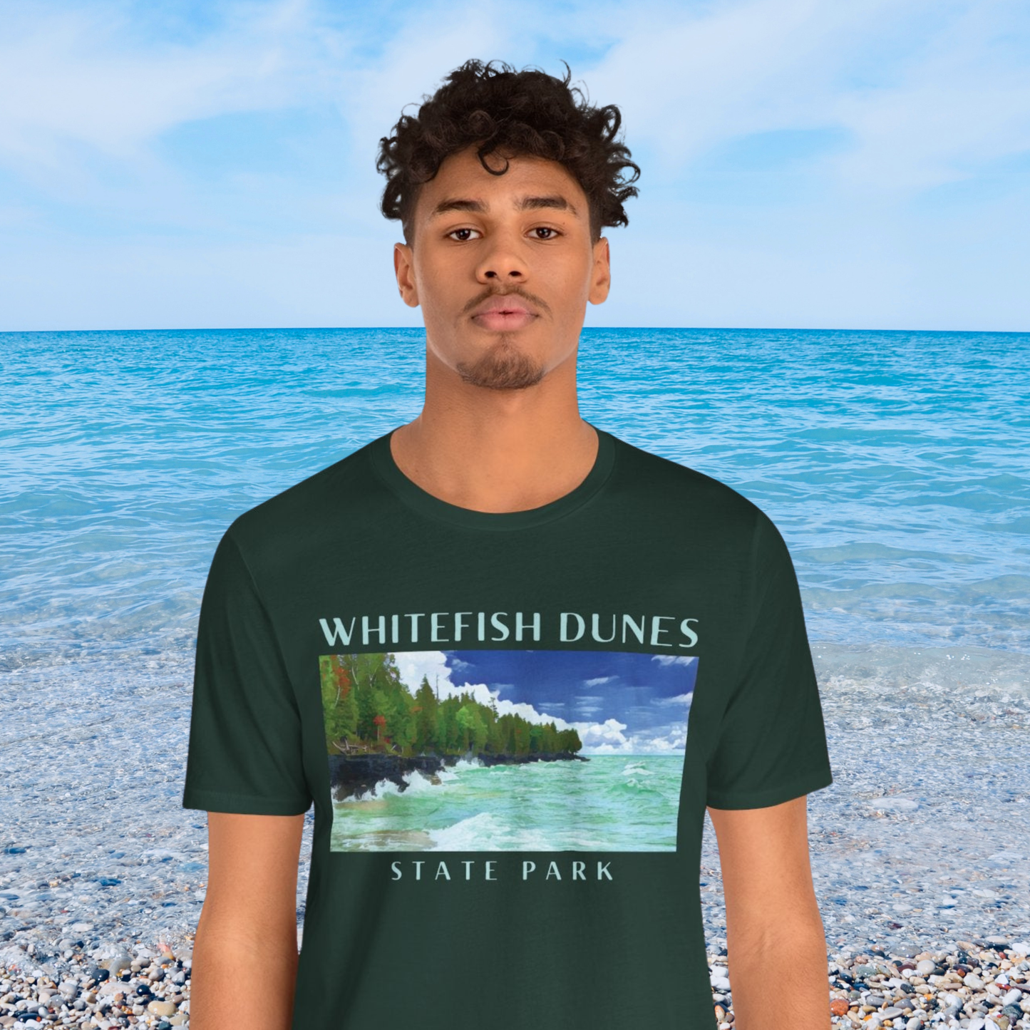 Person wearing a forest green t-shirt with Whitefish Dunes State Park design on a beach background