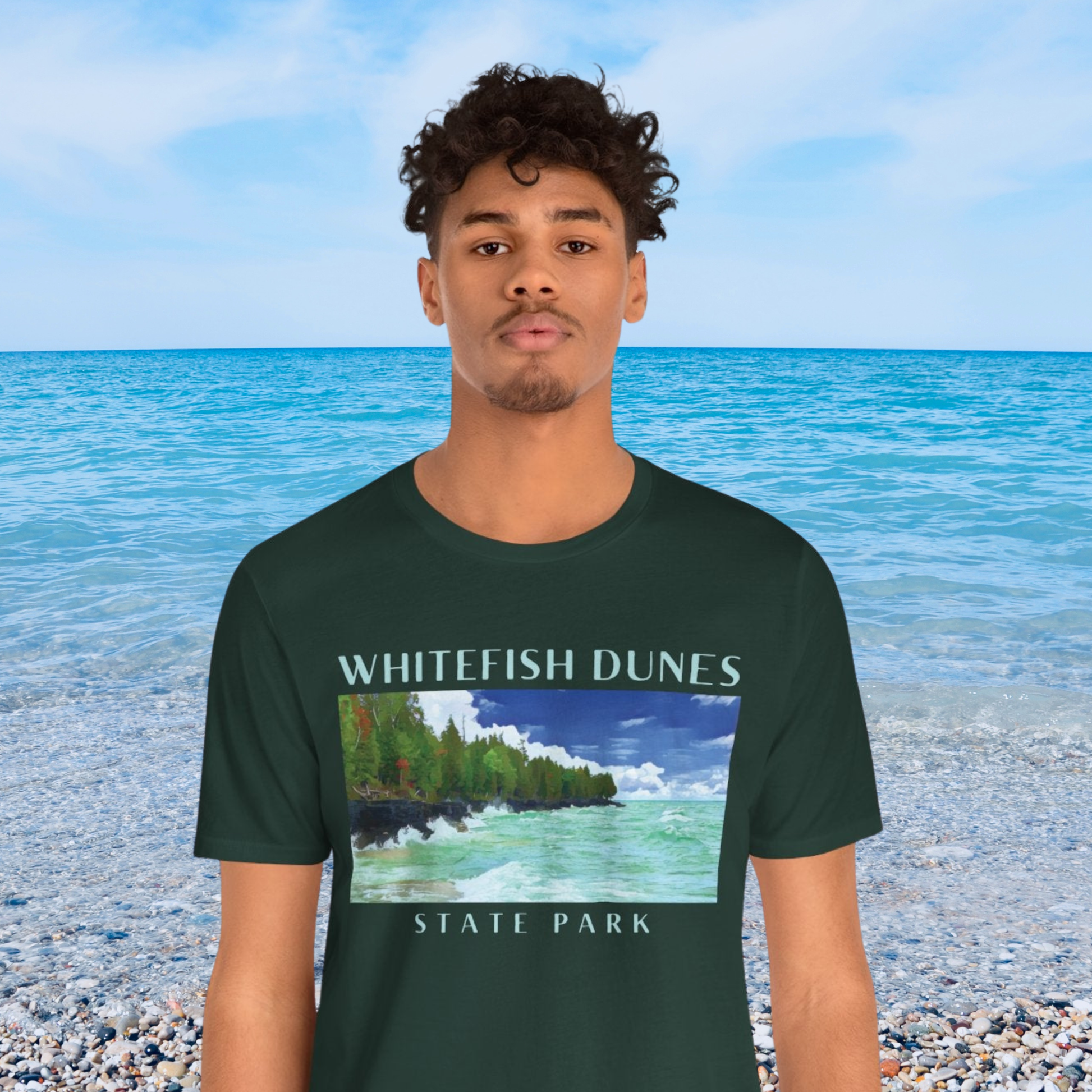 Person wearing a forest green t-shirt with Whitefish Dunes State Park design on a beach background