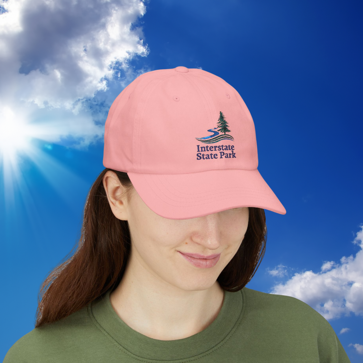 Person wearing a pink cap with 'Interstate State Park' logo against a blue sky.