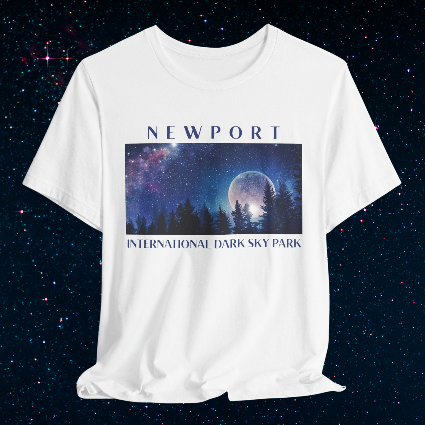 White t-shirt with a graphic of a moonlit forest and 'Newport International Dark Sky Park' text on a starry night background.