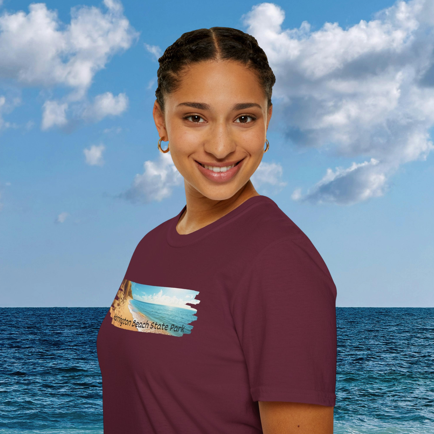 Person wearing a maroon t-shirt with a graphic design against a blue sky and ocean background