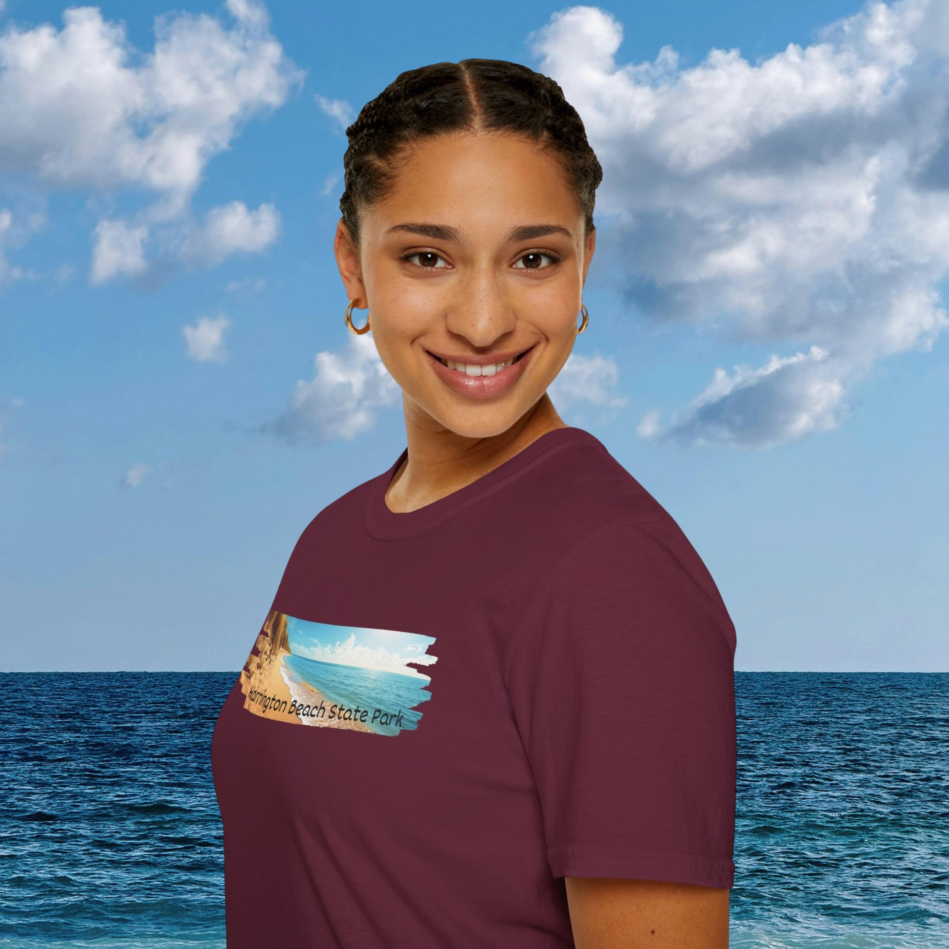 Person wearing a maroon t-shirt with a graphic design against a blue sky and ocean background