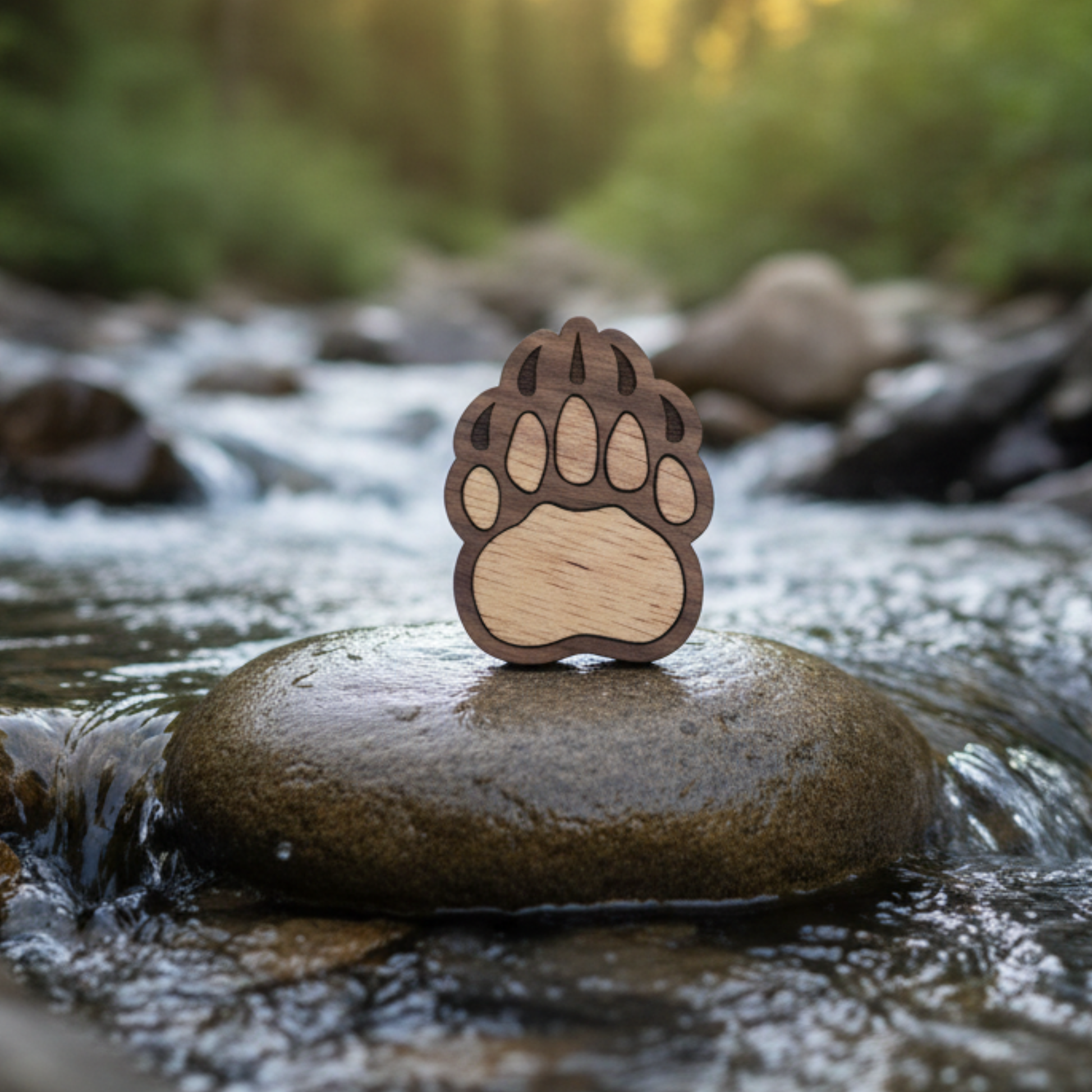 Wooden bear paw magnet on a rock in a stream with a blurred natural background.