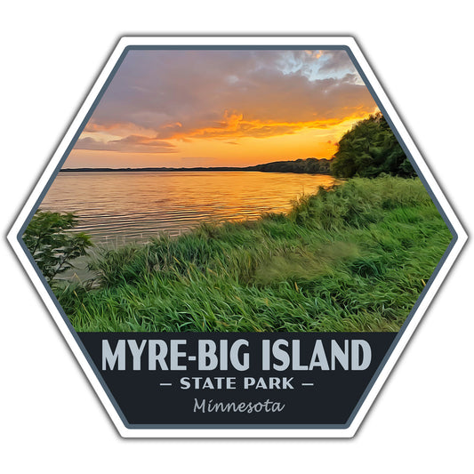 A hexagonal sticker or patch design featuring a scenic sunset over a lake with grassy shoreline, plus the text 'MYRE-BIG ISLAND - STATE PARK - Minnesota' on a dark band at the bottom.