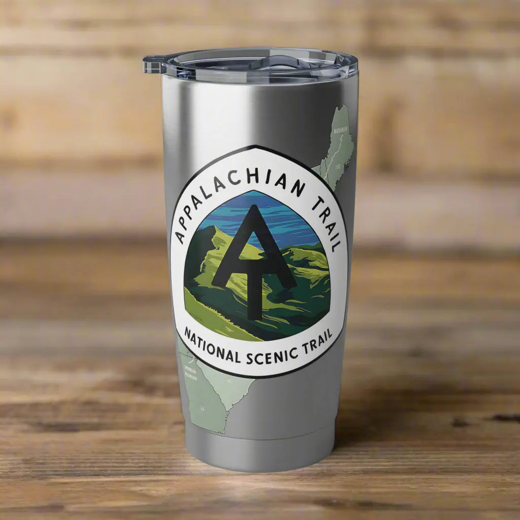 Stainless steel tumbler with Appalachian trail logo and map design set on a wood table.