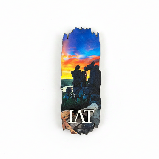 A vertical rectangular magnet featuring a colorful sunset scene with silhouetted rock formations and the text 'IAT' in white at the bottom, shown on a plain white background.