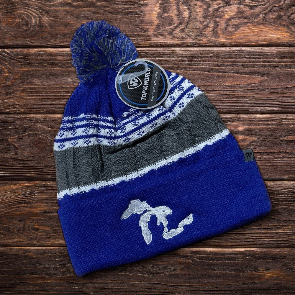 Blue and gray striped knit beanie with pom-pom on a wooden surface